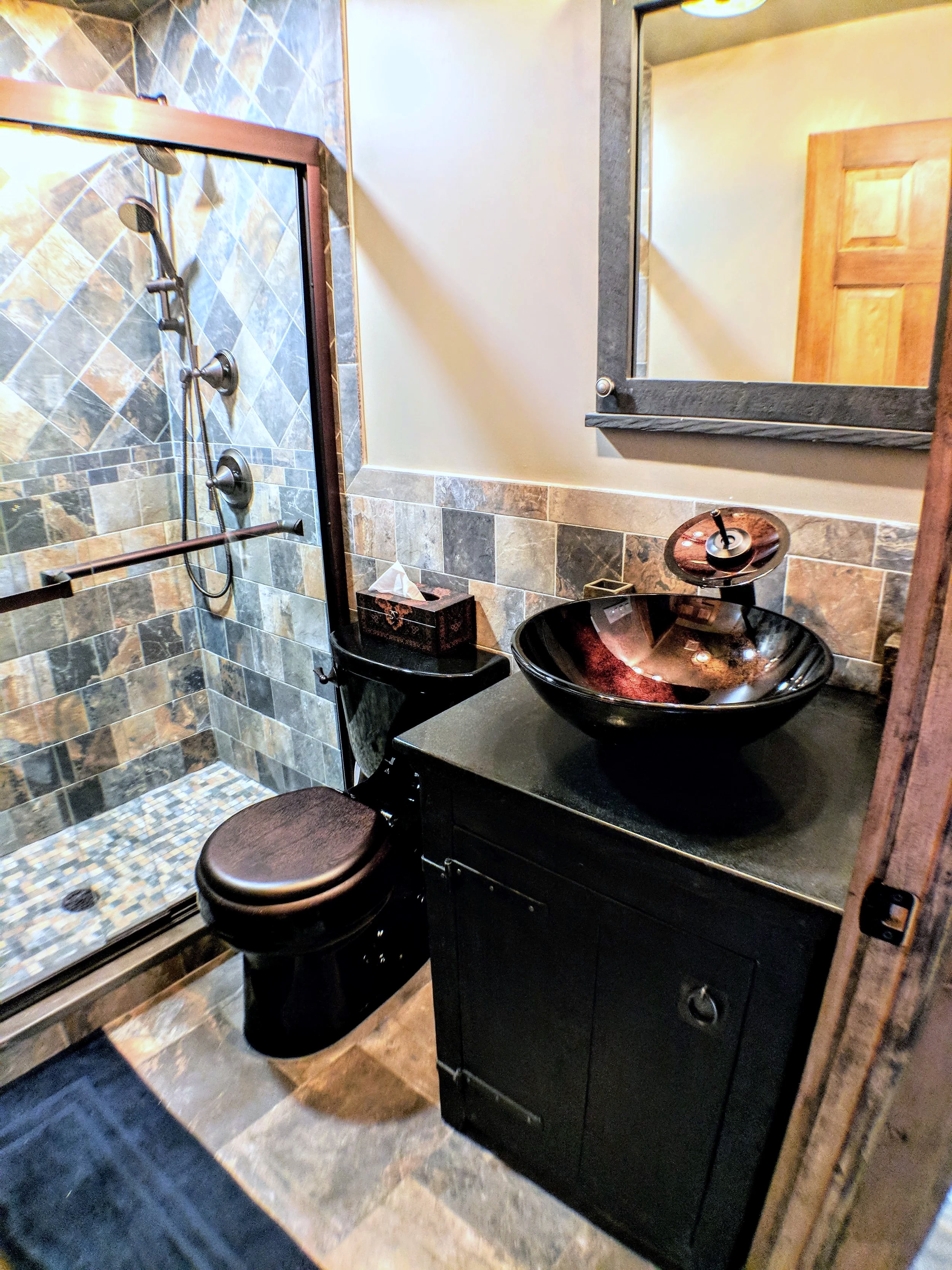 Bathroom with slate tile shower, black vanity and vessel sink